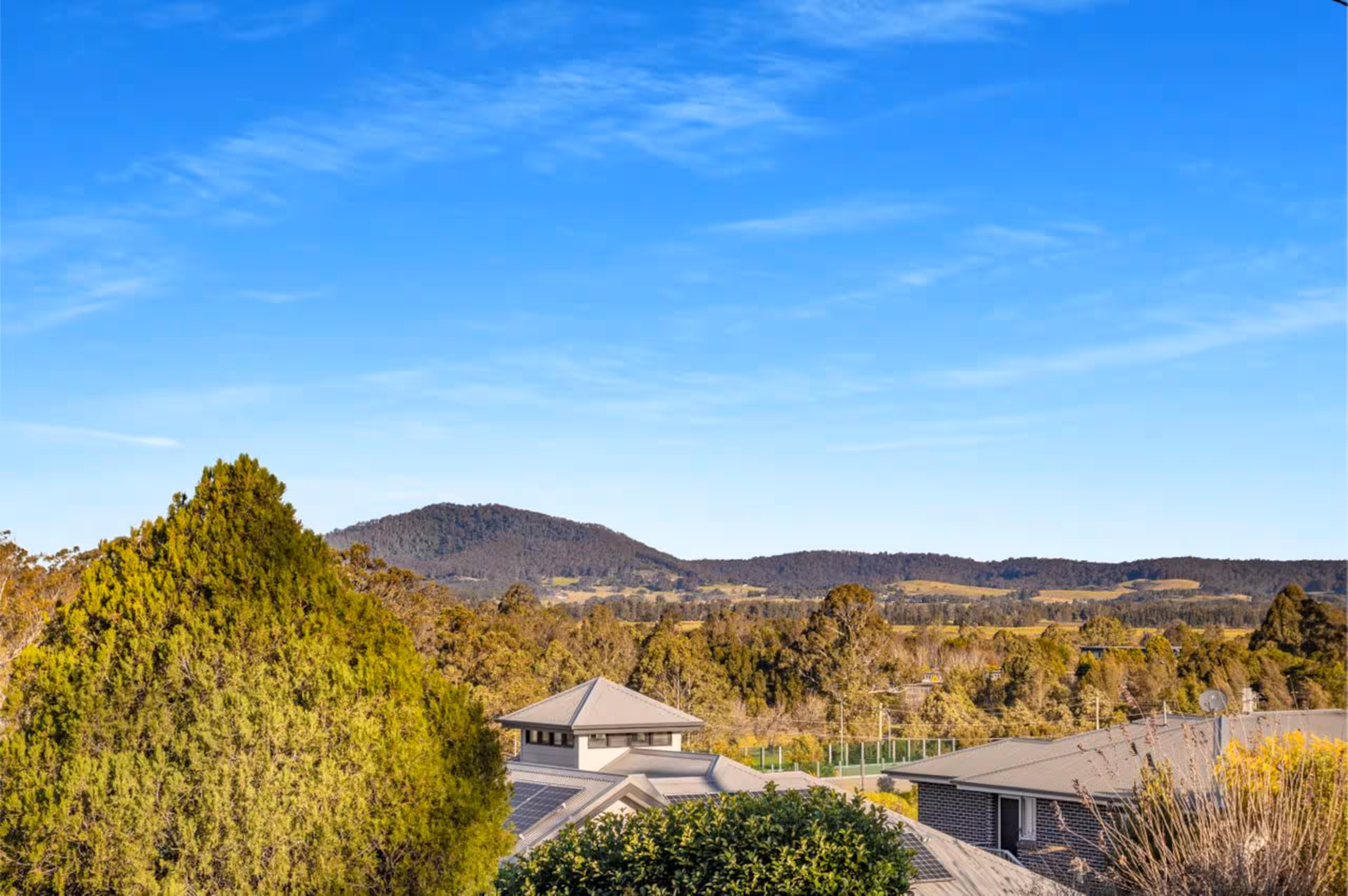 Elevated view across the rooftops and treetops to Coolangatta Mountain under a clear sky.